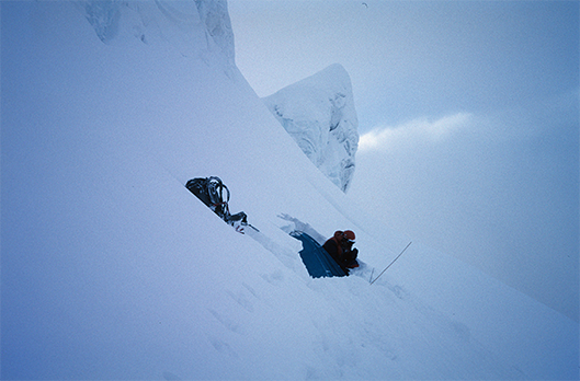 Artur Hajzer obok namiotu przykrytego śniegiem