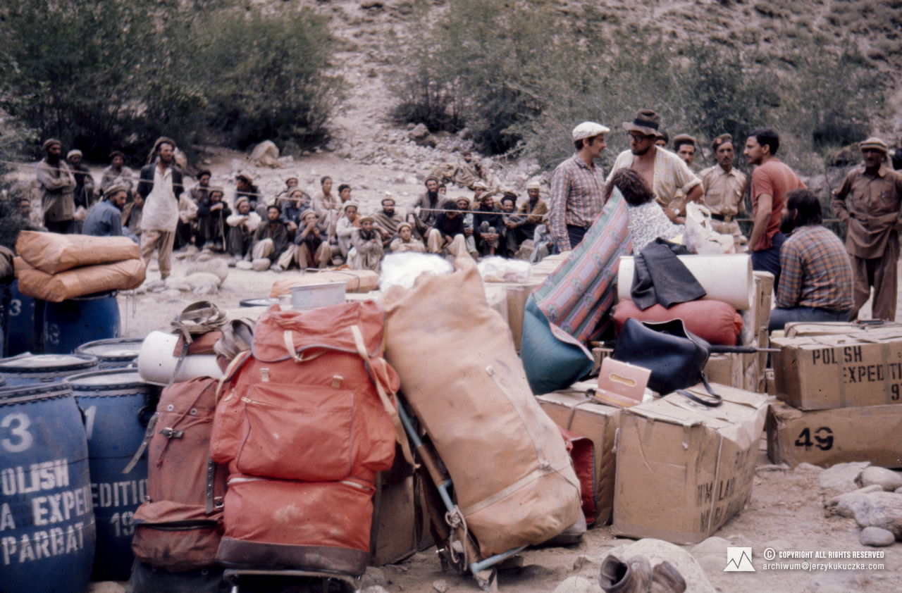 Allocation of cargo to porters. On the right from the left: Adam Zyzak, Danuta Wach (seating), Jan Koisar, two Pakistani soldiers, Shoaib Hameed and Janusz Majer (seating).